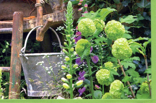 Blankokarte mit grünem Blumenmotiv und nostalgischem Zinkeimer als Gartenidylle für persönliche Grüße oder Glückwünsche