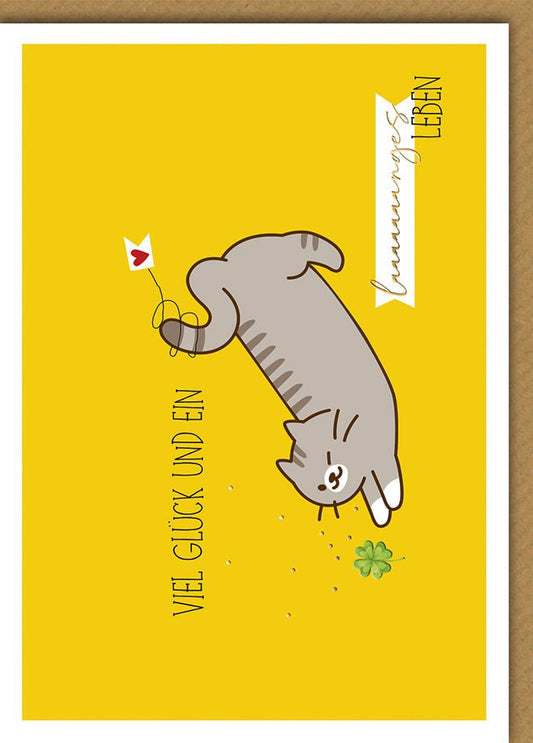 Geburtstagskarte Viel Glück – Verspielte Katze mit Kleeblatt auf gelbem Hintergrund