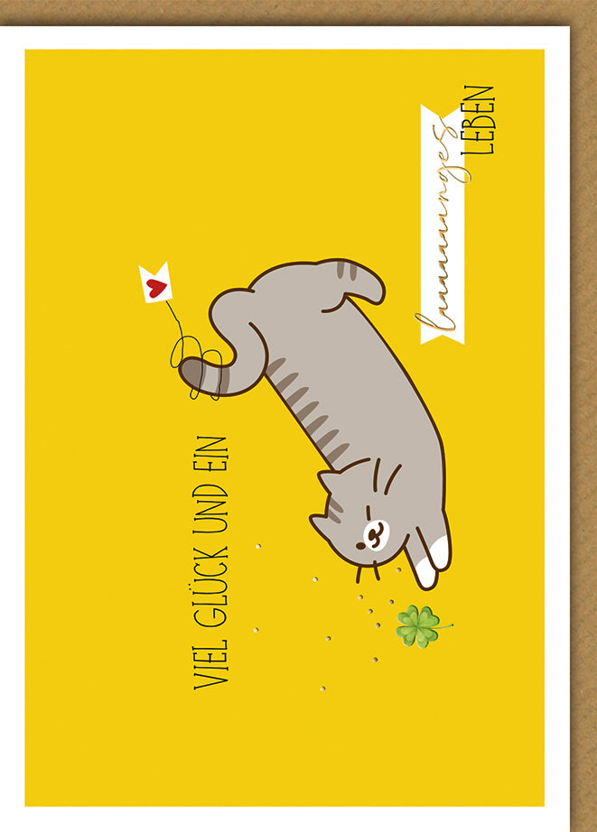 Geburtstagskarte Viel Glück – Verspielte Katze mit Kleeblatt auf gelbem Hintergrund