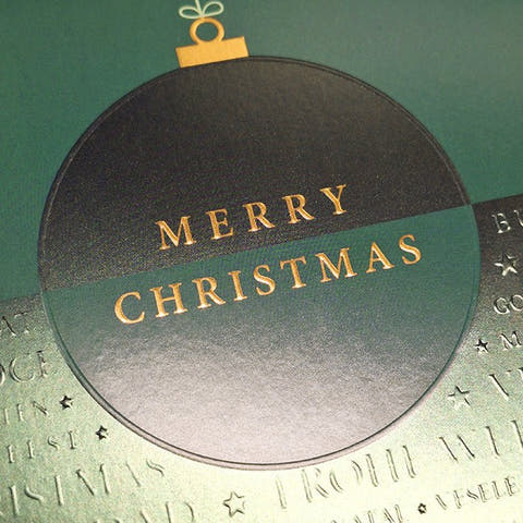 Weihnachtskarte mit eleganter grüner Christbaumkugel und festlichem Schriftzug
