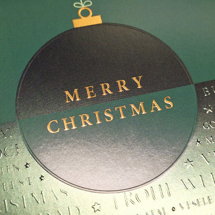 Weihnachtskarte mit eleganter grüner Christbaumkugel und festlichem Schriftzug