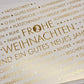 Weihnachtskarte mit festlichem Schriftzug und goldenen Sternen für frohe Feiertage