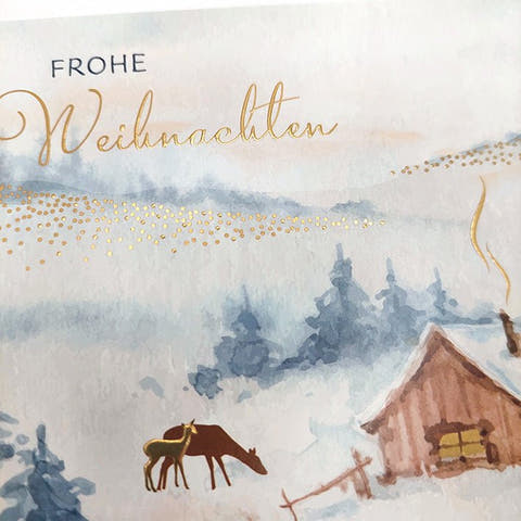 Weihnachtskarte mit idyllischer Winterlandschaft und leuchtendem Holzhaus